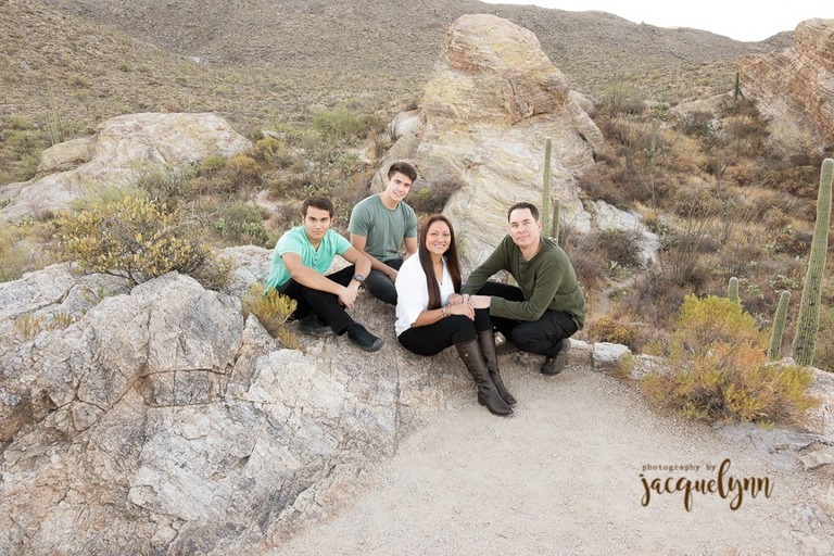 family sitting on a large rock in the middle of the tucson desert