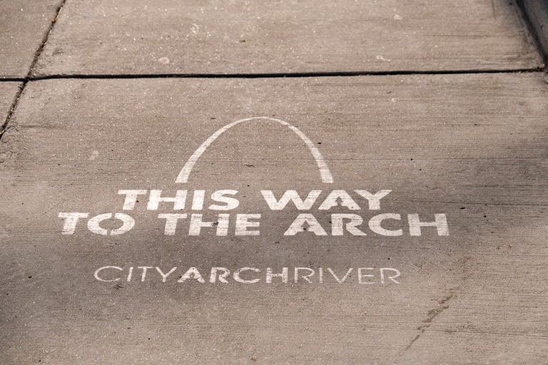 this way to the arch sign on sidewalk