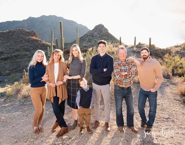 family of 7 standing on a rock with saguaros and mountains behind them