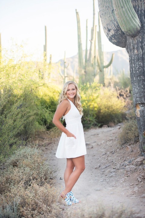 high school senior standing in the saguaro forest wearing a white dress