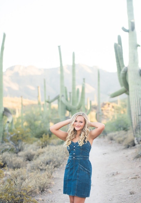 high shool senior girl wearing blue in the desert among the saguaros.