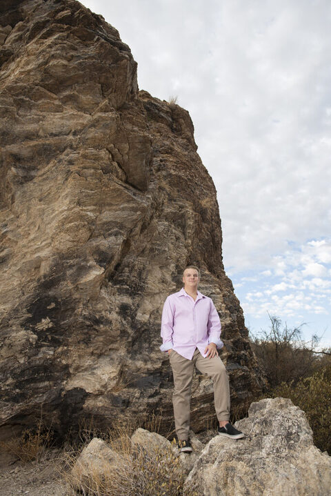 boy standing on rock wearing a pink shirt for his tucson senior pictures