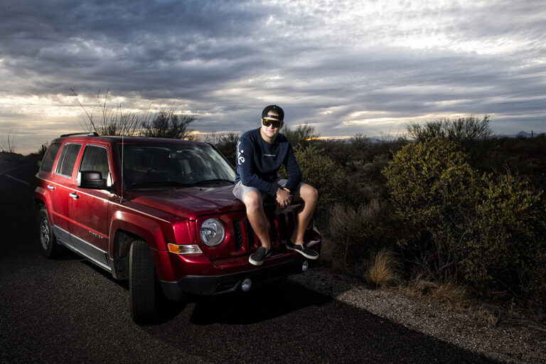 boy on his jeep wearing sunglasses and sitting on the hood for his tucson senior pictures for guys