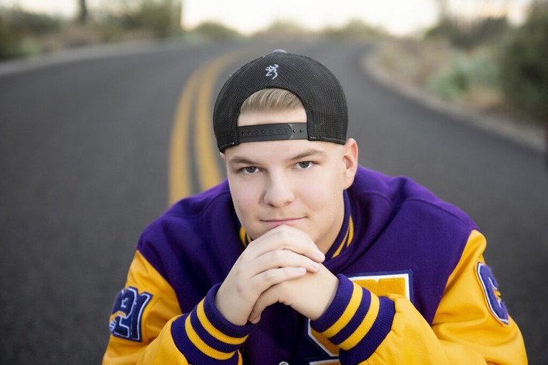 boy wearing varsity letter jacket close up on his face with a backwards hat