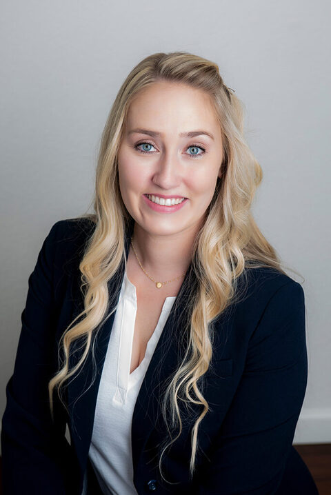 blond woman with blue eyes wearing a navy business suit