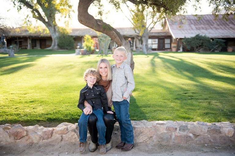 morning at tanque verde ranch tucson family photo session mother and sons sitting by grass in front of main ranch buildings