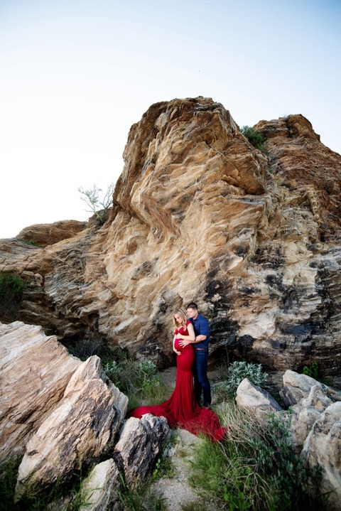 dramatic tucson maternity photo of pregnant woman in red dress and man by rocks