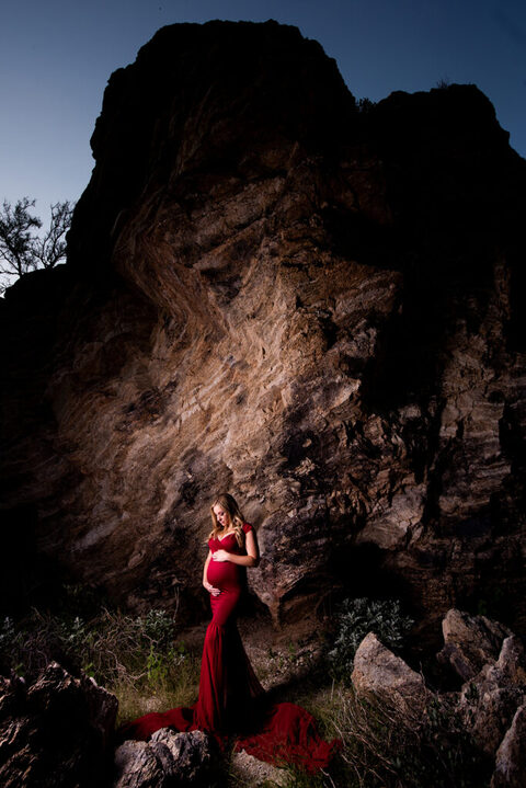 dramatic tucson maternity photo of pregnant woman in red dress by rocks