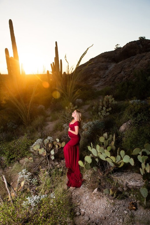 dramatic tucson maternity photo of pregnant woman in red dress at sunset in green desert