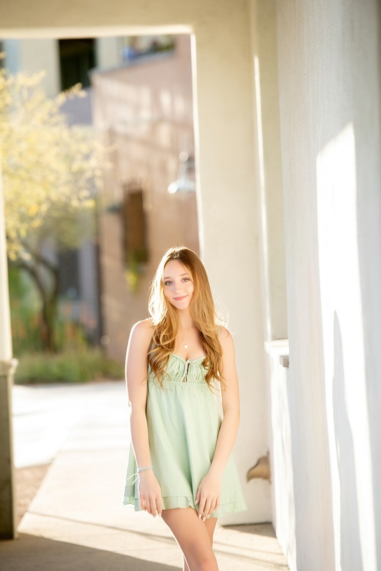 backlit high school senior girl wearing a green dress
