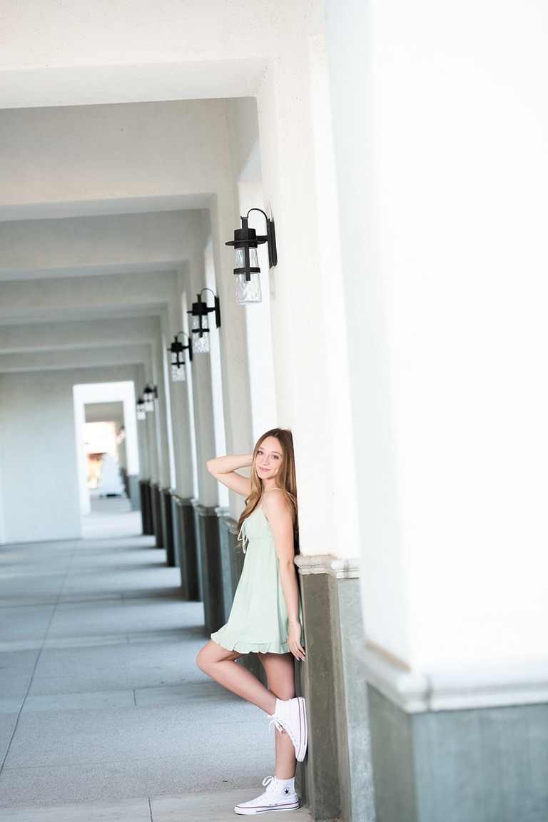 girl in green dress leaning against wall with columns